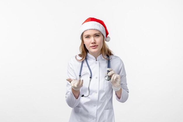 Front view of female doctor with stethoscope on a white wall