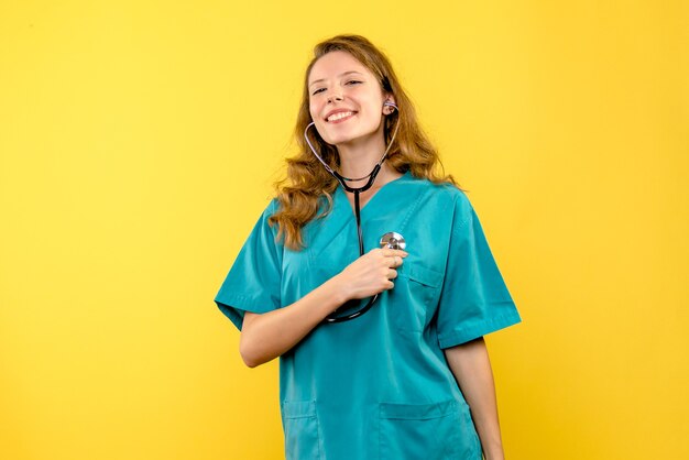Front view female doctor with stethoscope on a yellow space