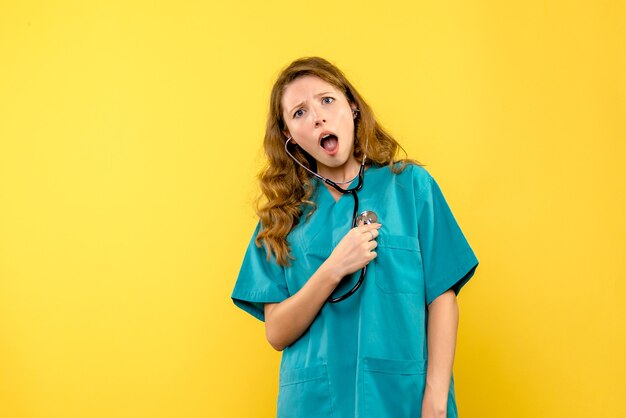 Front view female doctor with stethoscope on yellow space