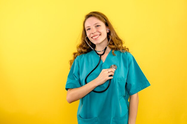 Front view female doctor with stethoscope on yellow space