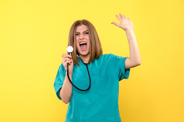 Front view of female doctor with tonometer on yellow wall