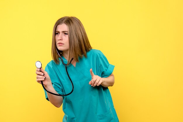 Front view of female doctor with tonometer on yellow wall