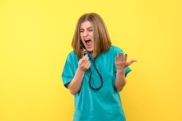 Front view of female doctor with tonometer on yellow wall