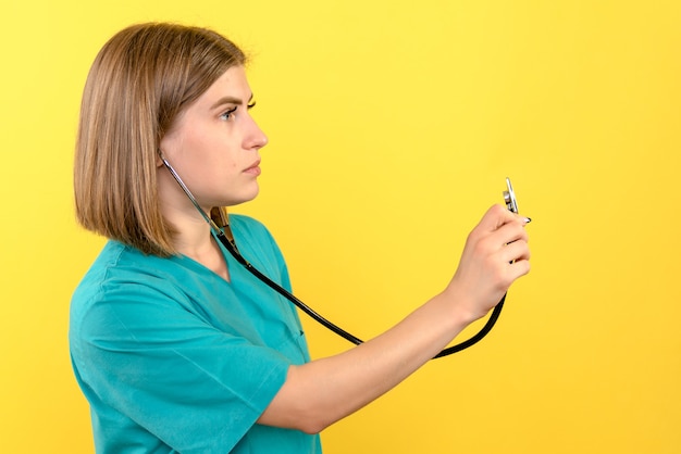 Front view of female doctor with tonometer on yellow wall