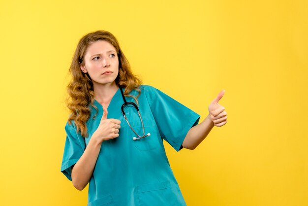 Front view of female doctor on a yellow wall