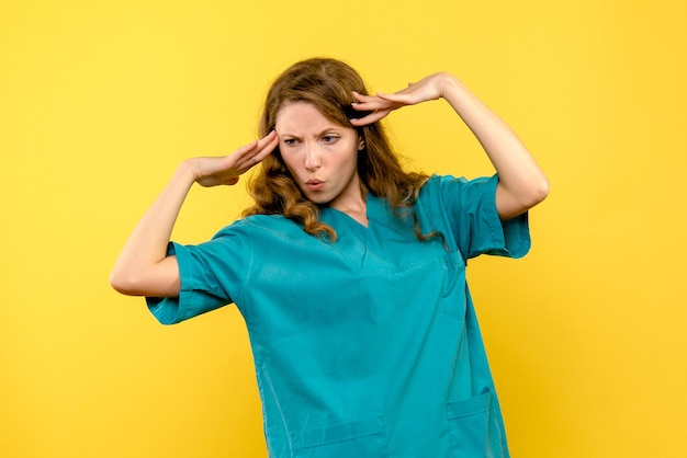 Front view of female doctor on a yellow wall