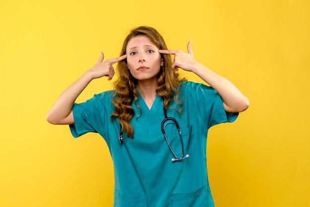 Front view of female doctor on yellow wall