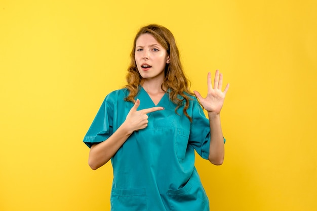 Front view of female doctor on yellow wall