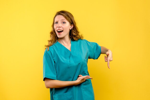 Front view of female doctor on yellow wall