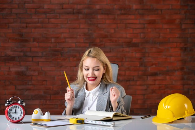 Front view female engineer sitting behind her working place