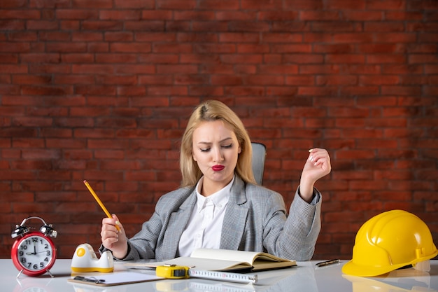 Assistente tecnico femminile di vista frontale che si siede dietro il suo posto di lavoro