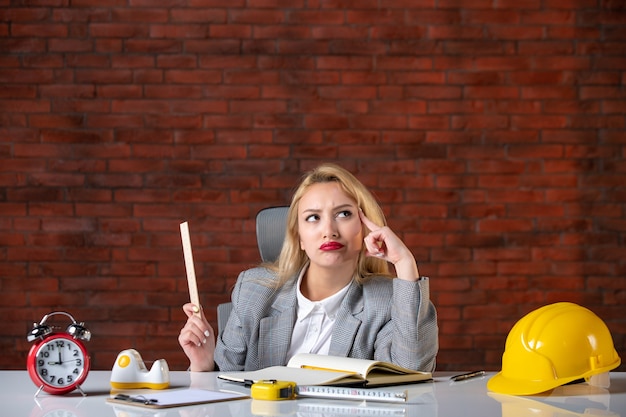 Front view female engineer sitting behind her working place