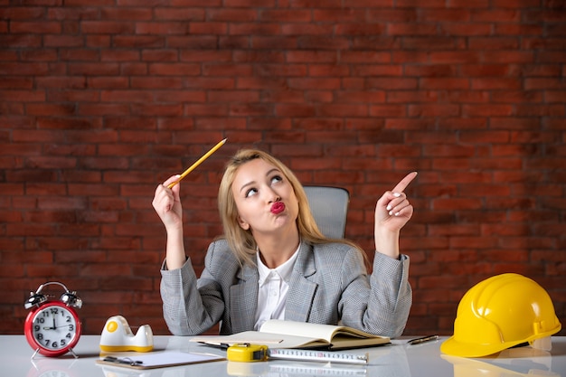 Front view female engineer sitting behind her working place