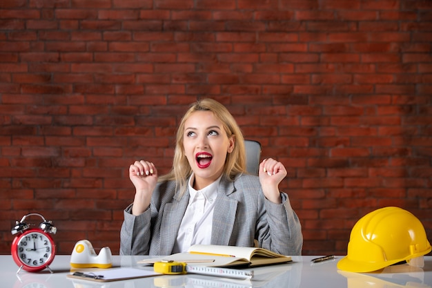 Foto gratuita assistente tecnico femminile di vista frontale che si siede dietro il suo posto di lavoro