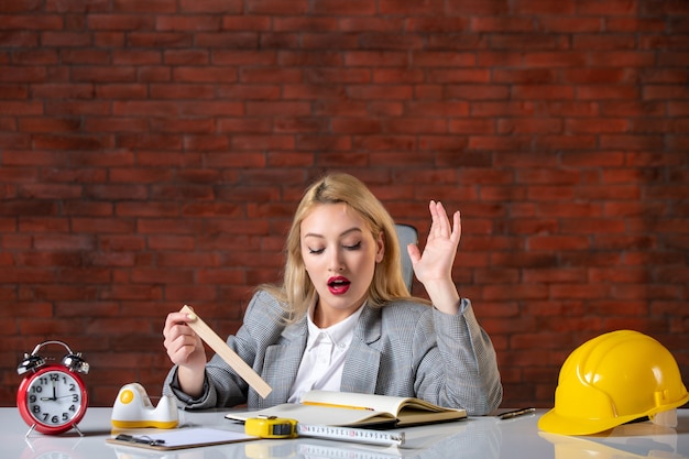 Foto gratuita assistente tecnico femminile di vista frontale che si siede dietro il suo posto di lavoro