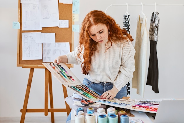 Vista frontale della stilista femminile che lavora con la tavolozza dei colori in atelier