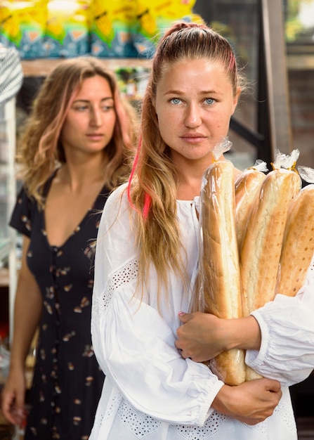 Front view of female friends holding bread baguettes