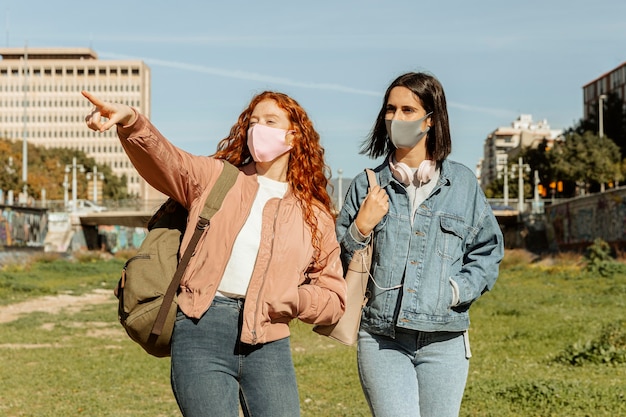 Free photo front view of female friends with face masks outdoors together