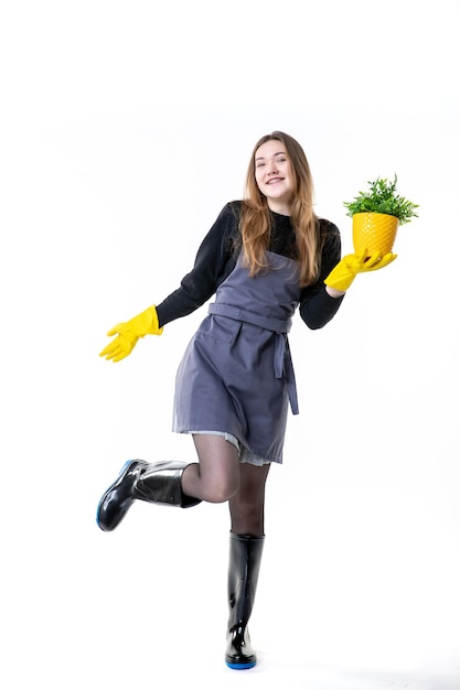 Front view female gardener in yellow gloves holding little plant on white