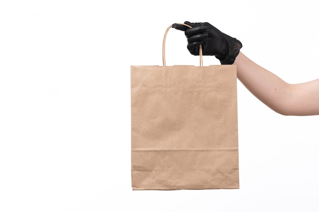 a front view female hand in black glove holding paper food package on white