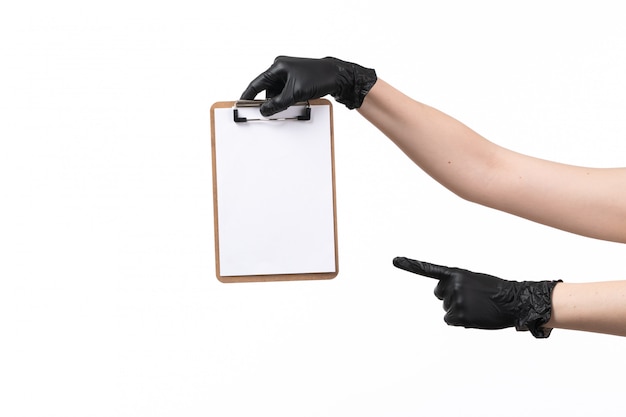 A front view female hand in black gloves holding notepad on white job