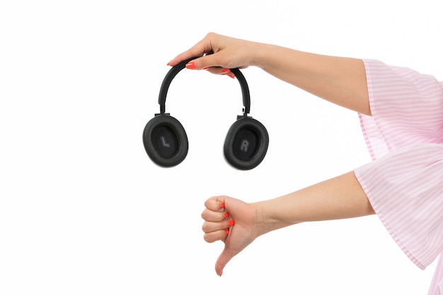 A front view female hand holding black earphones showing unlike sign on the white