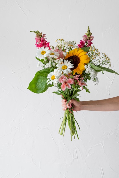 Vista frontale della mano femminile che tiene il mazzo di fiori