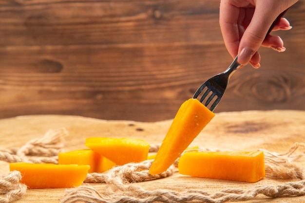 Front view female hand holding cheese on fork