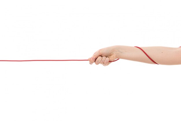 A front view female hand pulling up red rope on the white