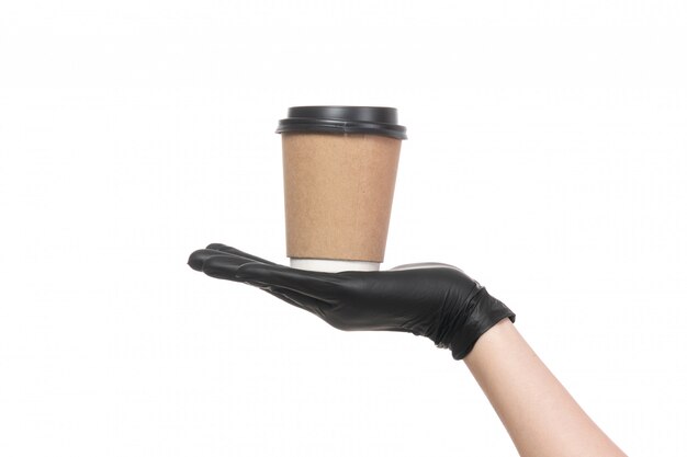 A front view female hand with black leather gloves holding cup of coffee on white