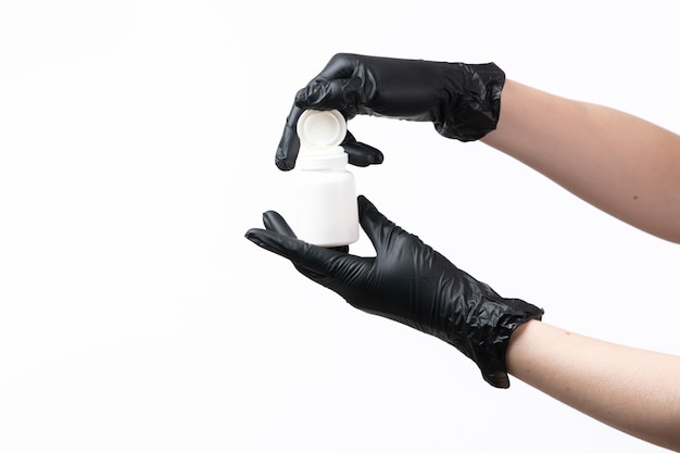 A front view female hands in black gloves holding white tube on white