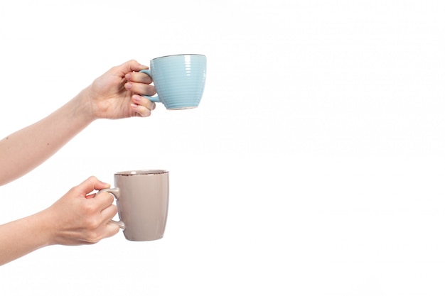 A front view female hands holding different colored cups on the white