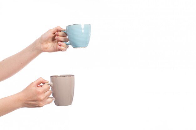 A front view female hands holding different colored cups on the white