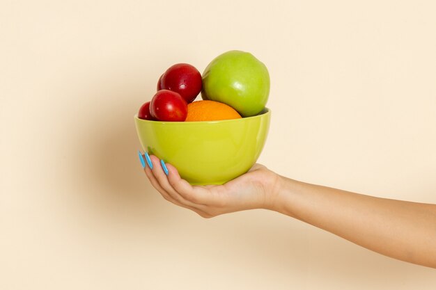 Front view female holding plate with different fruits on beige