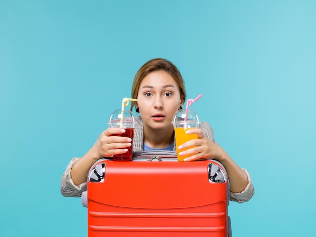 水色​の​背景​で​新鮮な​飲み物​を​保持している​休暇中​の​女性​の​正面図​旅行​航海​休暇​旅行​水上​飛行機
