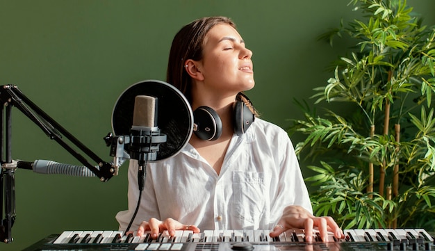 Front view of female musician playing piano keyboard indoors