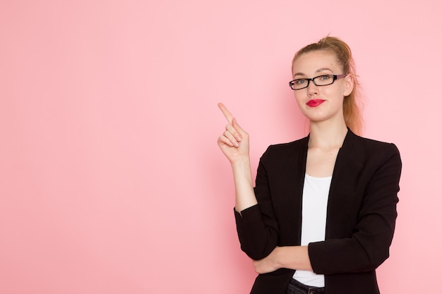 Free photo front view of female office worker in black strict jacket smiling and posing on pink wall