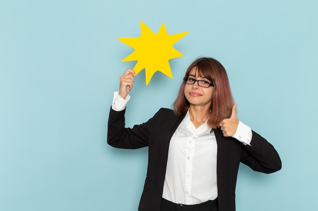 Front view female office worker holding big yellow sign on light-blue surface