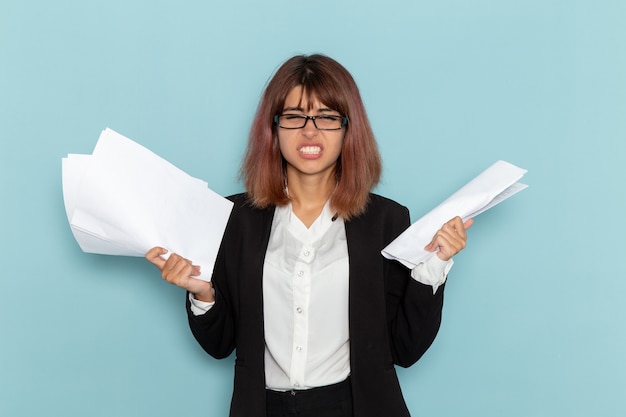 Free photo front view female office worker holding different paperwork on light-blue surface