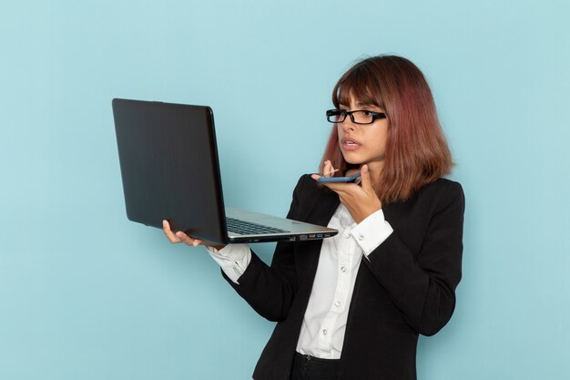 파란색 표면에 전화로 얘기하는 동안 노트북을 들고 전면보기 여성 회사원