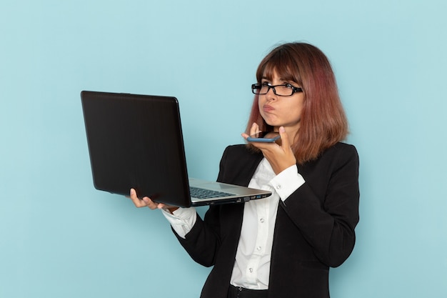 Vista frontale femminile impiegato in possesso di telefono e computer portatile sulla superficie blu