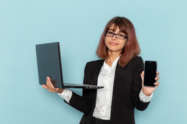 Вид спереди женский офисный работник, держащий смартфон и ноутбук на синей поверхности