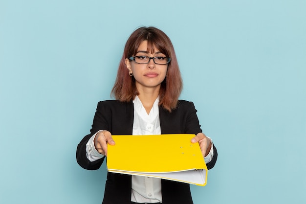 Front view female office worker holding yellow file on the blue surface