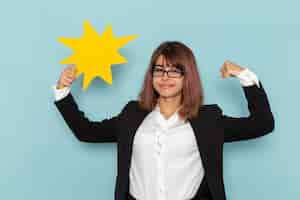 Free photo front view female office worker holding yellow sign and flexing on the blue surface