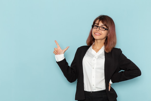 Front view female office worker smiling and posing on the blue surface