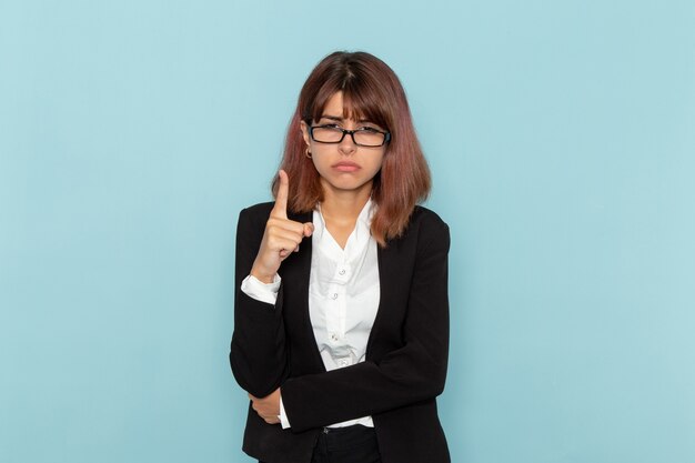 Front view female office worker in strict suit threatening on blue surface