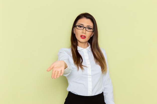 Front view of female office worker in white shirt and black skirt on green wall