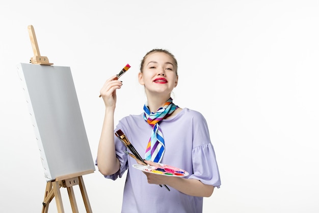 Front view female painter preparing to draw on white desk easel picture drawing artist pencil art paint