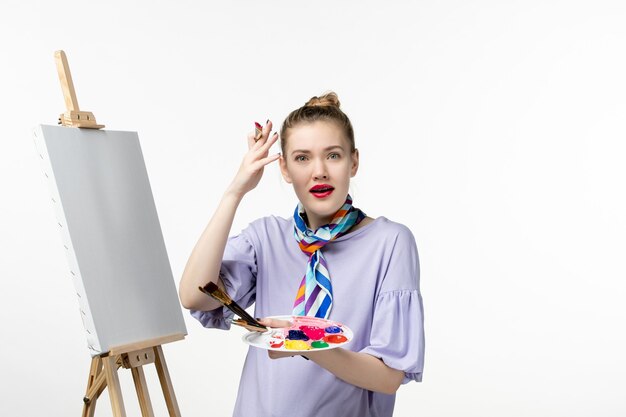 Front view female painter preparing to draw on white wall artist easel picture drawing art paint