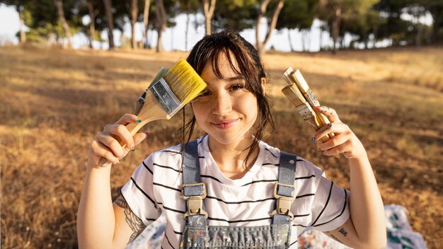 Front view of female painter with paintbrushes